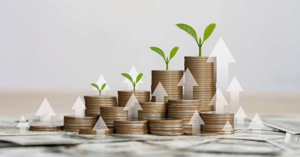 Pilas de monedas con brotes verdes y flechas ascendentes, simbolizando el crecimiento financiero.